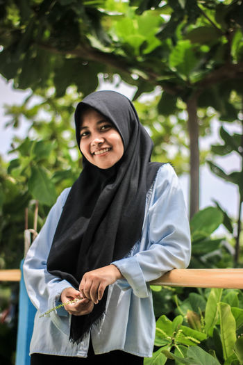 Portrait of smiling woman standing against plants
