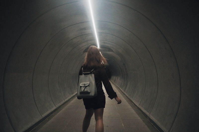 Rear view of woman standing in tunnel