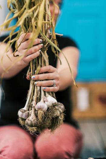 A woman holding up a bundle of cured garlic