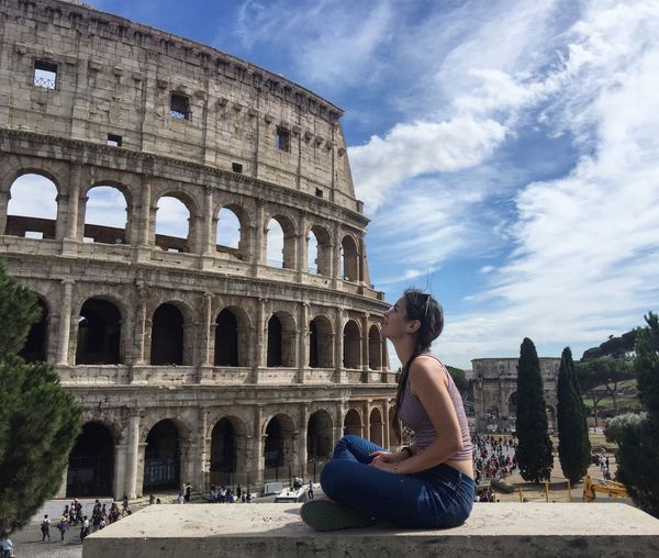 Full length of young woman looking at coliseum in city