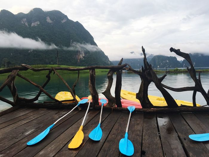 Oars on wooden pier by lake against mountains