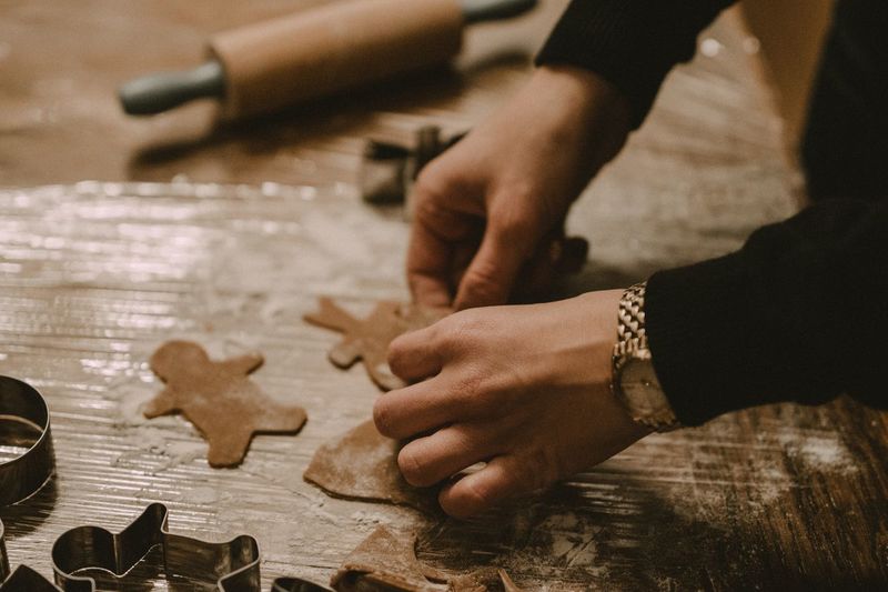 Cropped hands of man making gingerbread cookies on table