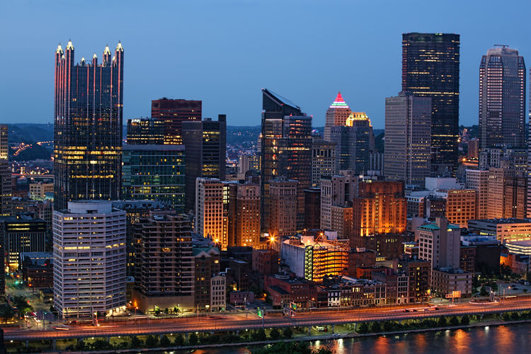 Illuminated buildings in city against sky at dusk