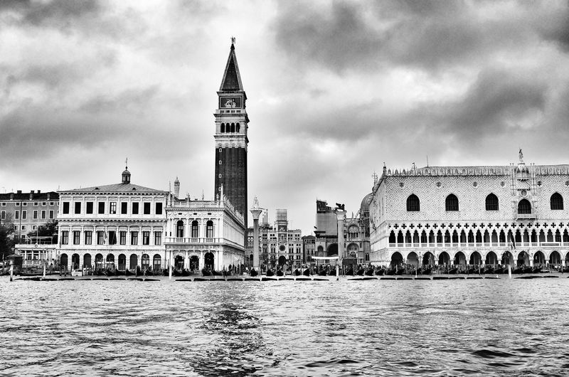 Grand canal by san marco campanile against cloudy sky