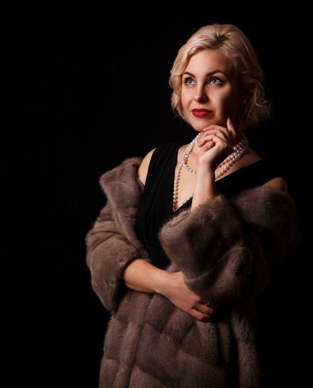 Portrait of young woman against black background