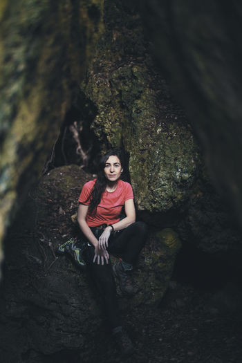 Portrait of young woman standing by tree trunk in forest