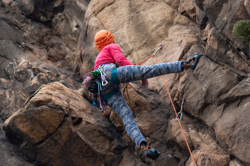 Lady climbing on the rock with equipment