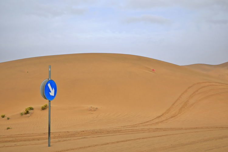 1026 traffic in the desert. mandatory direction sign among the dunes. badain jaran-nei mongol-china.