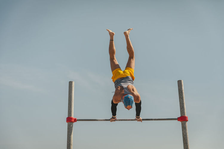Male gymnast doing handstand on high bar