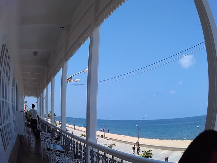 Fish-eye lens of man standing in balcony by sea against sky