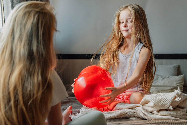 Little girl wishes a happy birthday to her girlfriend, sister in the morning, gives a heart balloon