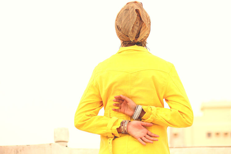 Rear view of man standing on yellow against sky