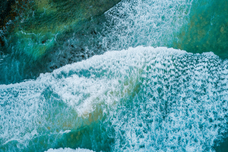 High angle view of sea waves covered by foam