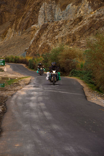 People riding motorcycles on road by mountain