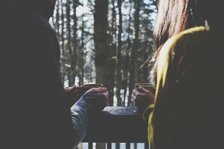 Rear view of people drinking coffee on balcony in winter