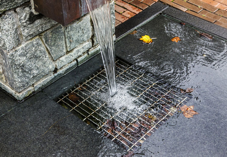 High angle view of water falling on wet metal fence