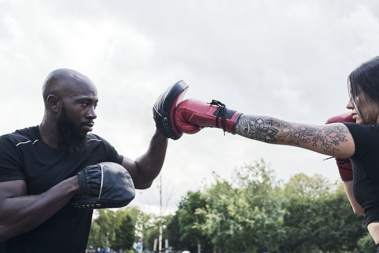 Strong brunette woman boxing outdoors with her personal coach.