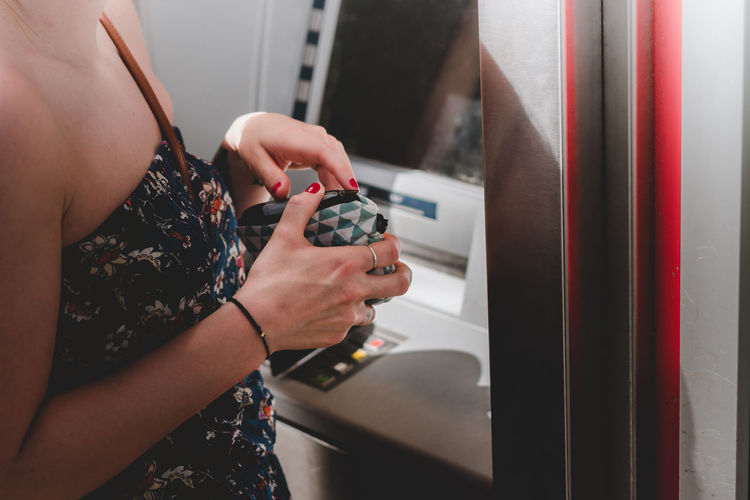 Close-up of woman hand holding purse at atm