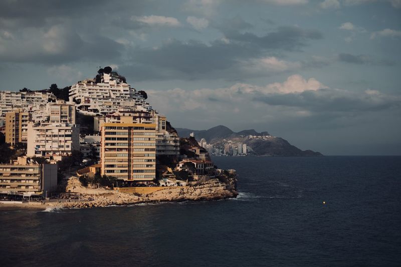 Buildings by sea against sky