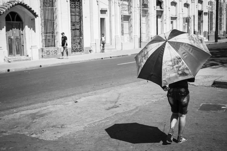 Rear view of woman with umbrella walking on street in city