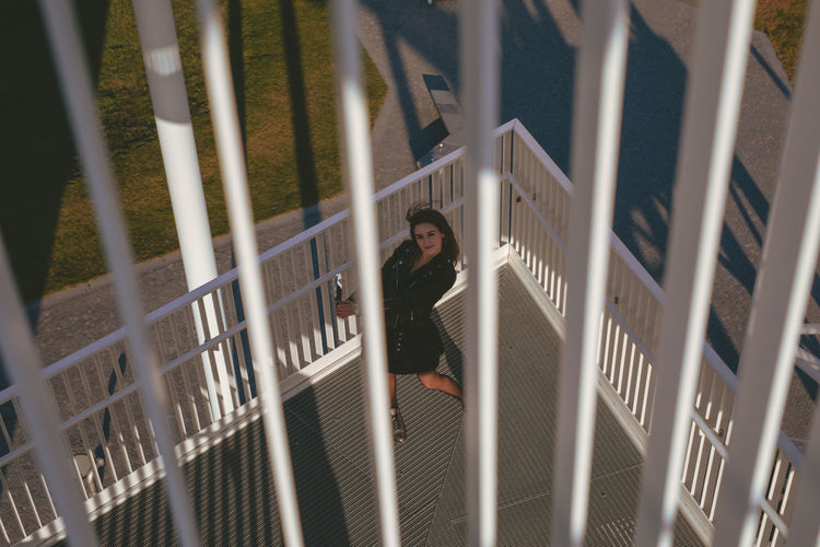 High angle portrait of young woman seen through railing