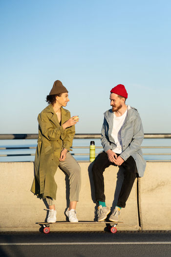 Young couple of hipster skateboarders relax after skateboarding training sitting on concrete bridge