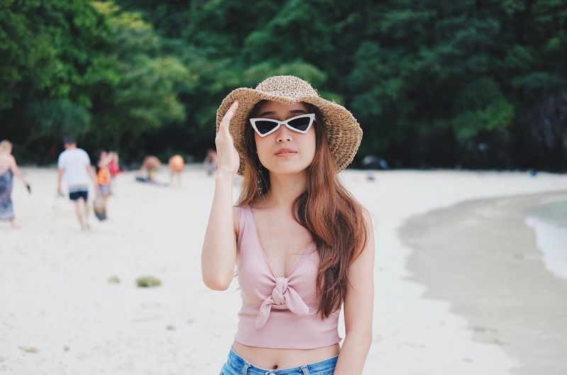 Portrait of beautiful young woman wearing sunglasses standing outdoors