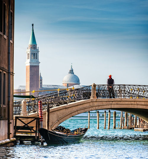 Rear view of man standing on footbridge over canal by church of san giorgio maggiore