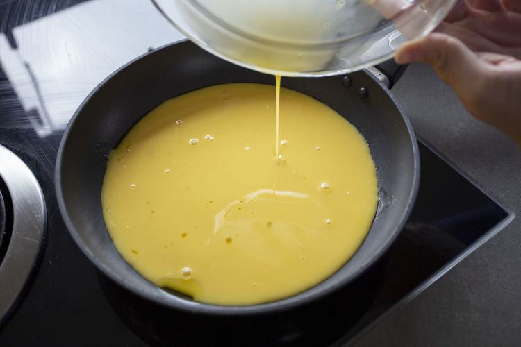 Pouring beaten eggs into a frying pan