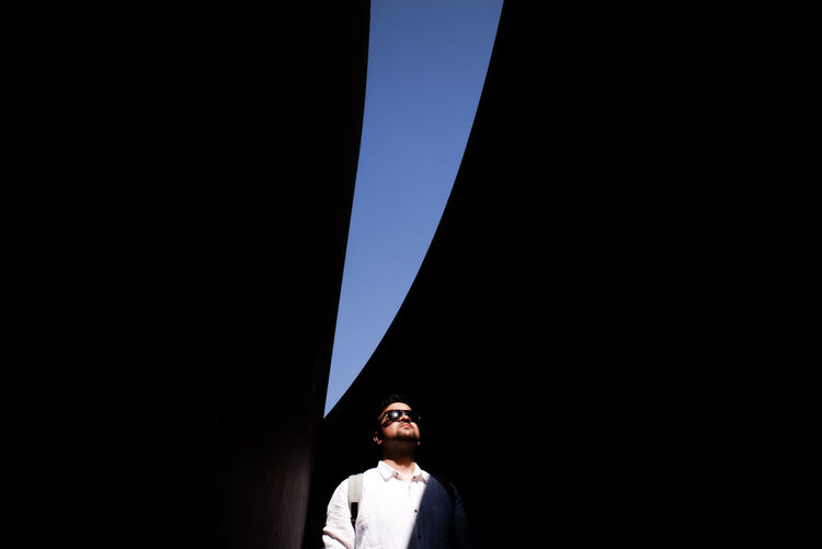 Young man standing below bridge