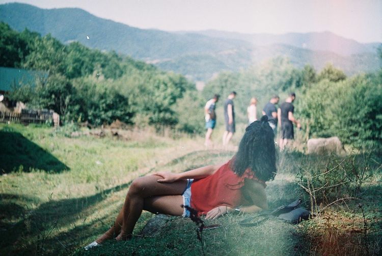 Woman looking at friends while leaning on field