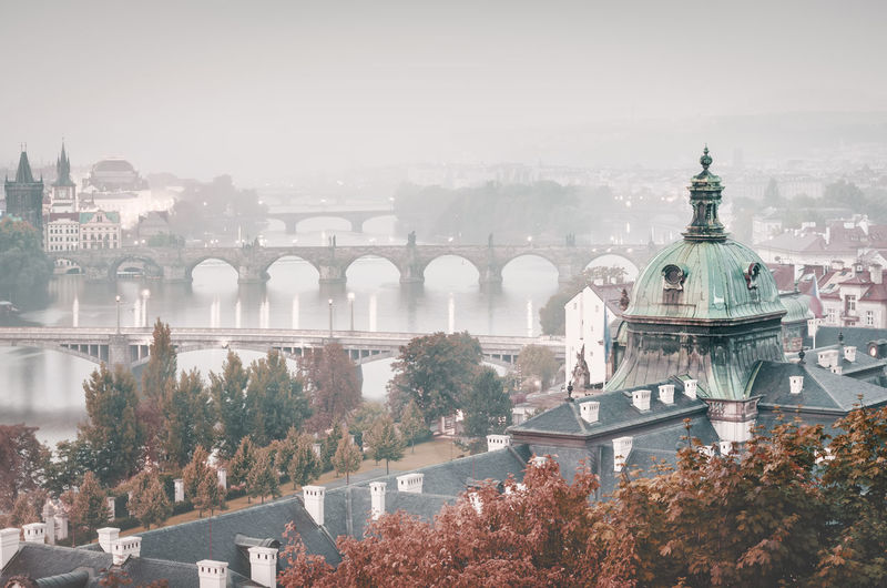Charles bridge over vltava river against sky during foggy weather