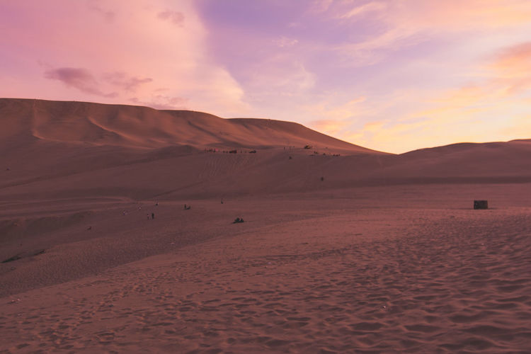 Sand dunes in desert against cloudy sky