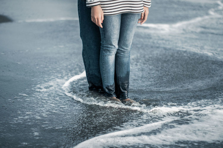 Low section of couple standing at shore
