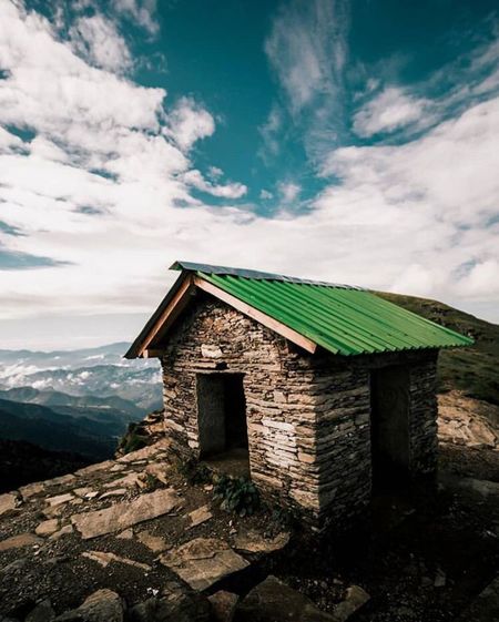 Old house on building by mountain against sky
