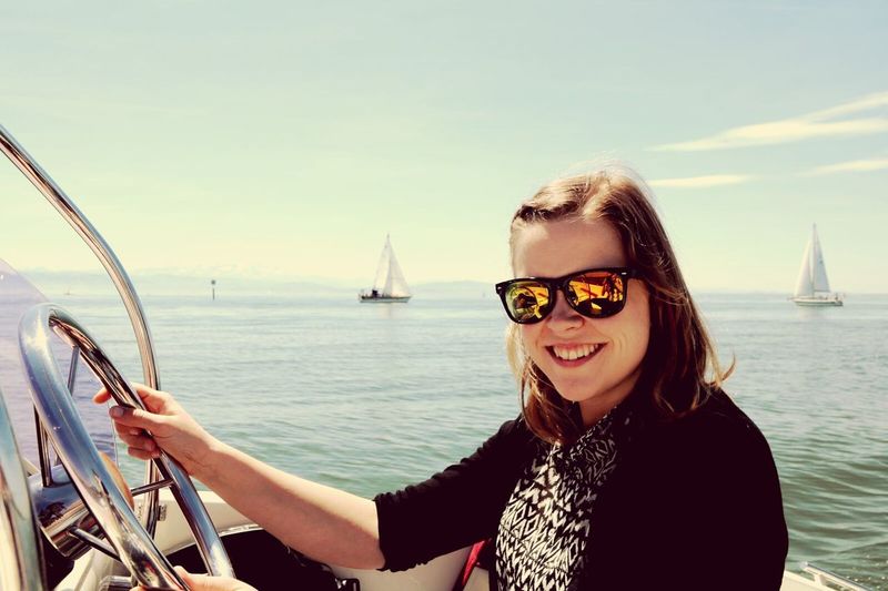 Close-up of happy woman helming boat on sea against sky