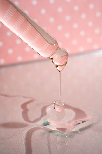 A dripping pipette with a drop of cosmetics gel.