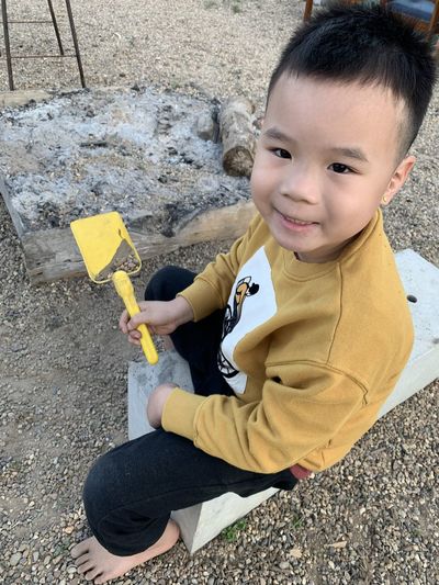 Portrait of boy holding yellow while sitting outdoors