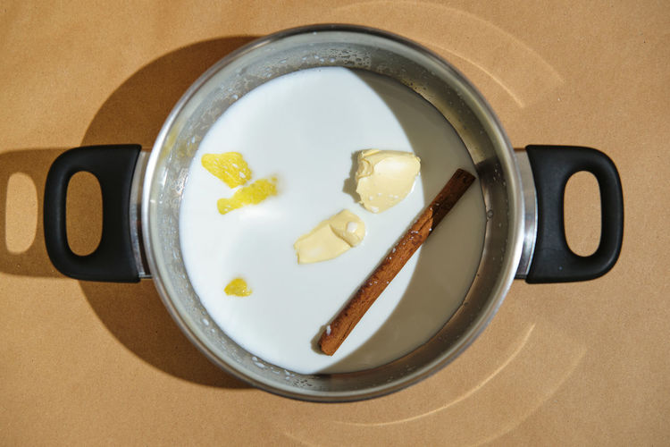 Steel pot prepared with cinnamon, lemon and butter for pouring milk an