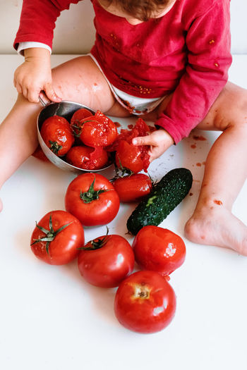 High angle view of baby with crushed tomatoes on table