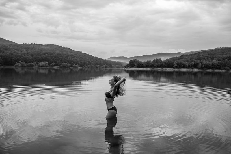 Woman standing in lake against sky
