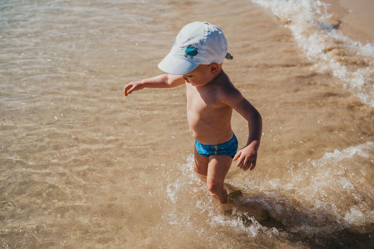 Boy walking into the water at the beach on a sunny day on vacation