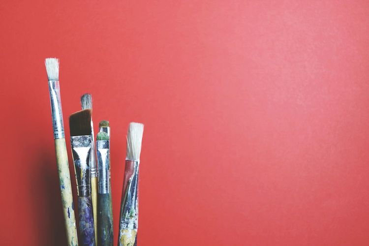 Close-up of paintbrushes against red background