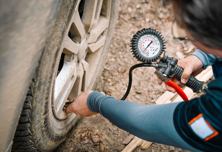 Person checking tire pressure with gauge instrument
