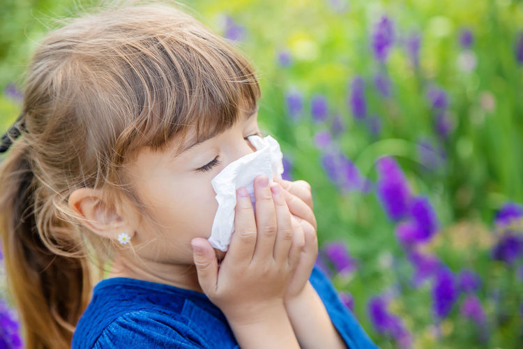 Sick girl having allergy wiping nose