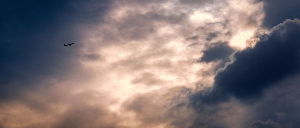 Low angle view of silhouette airplane against sky