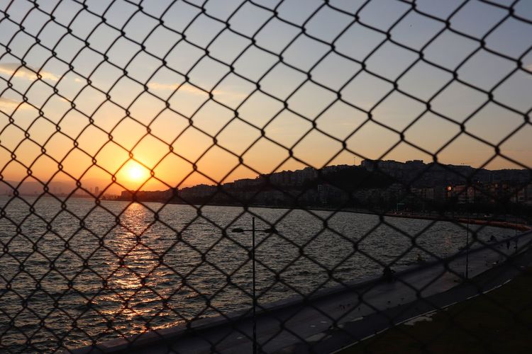 Scenic view of sea seen through chainlink fence