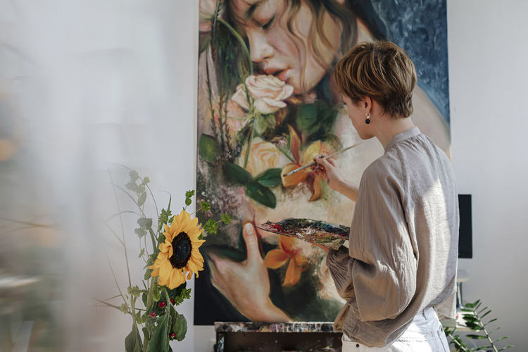 Mid adult female artist painting on canvas in studio