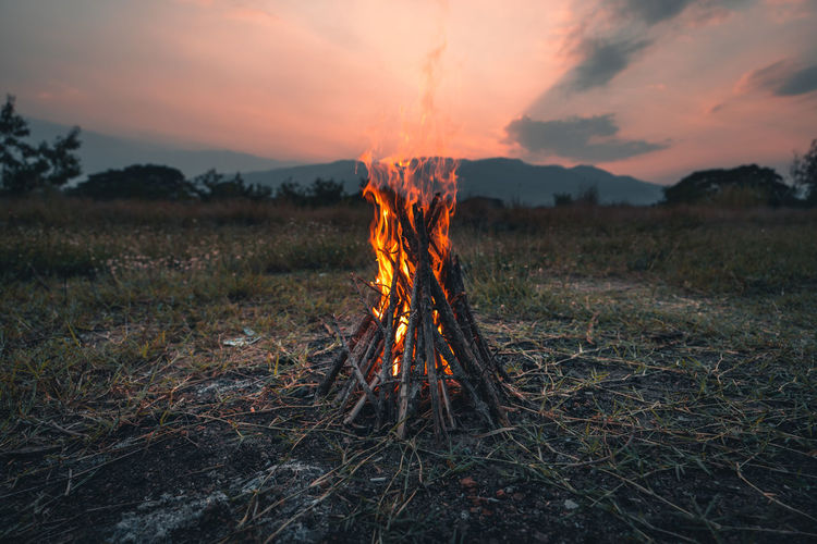 Bonfire on field against sky at sunset