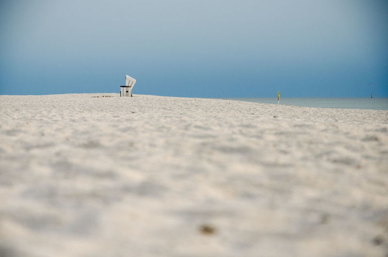 Mid distance view of hooded beach chair at beach against blue sky
